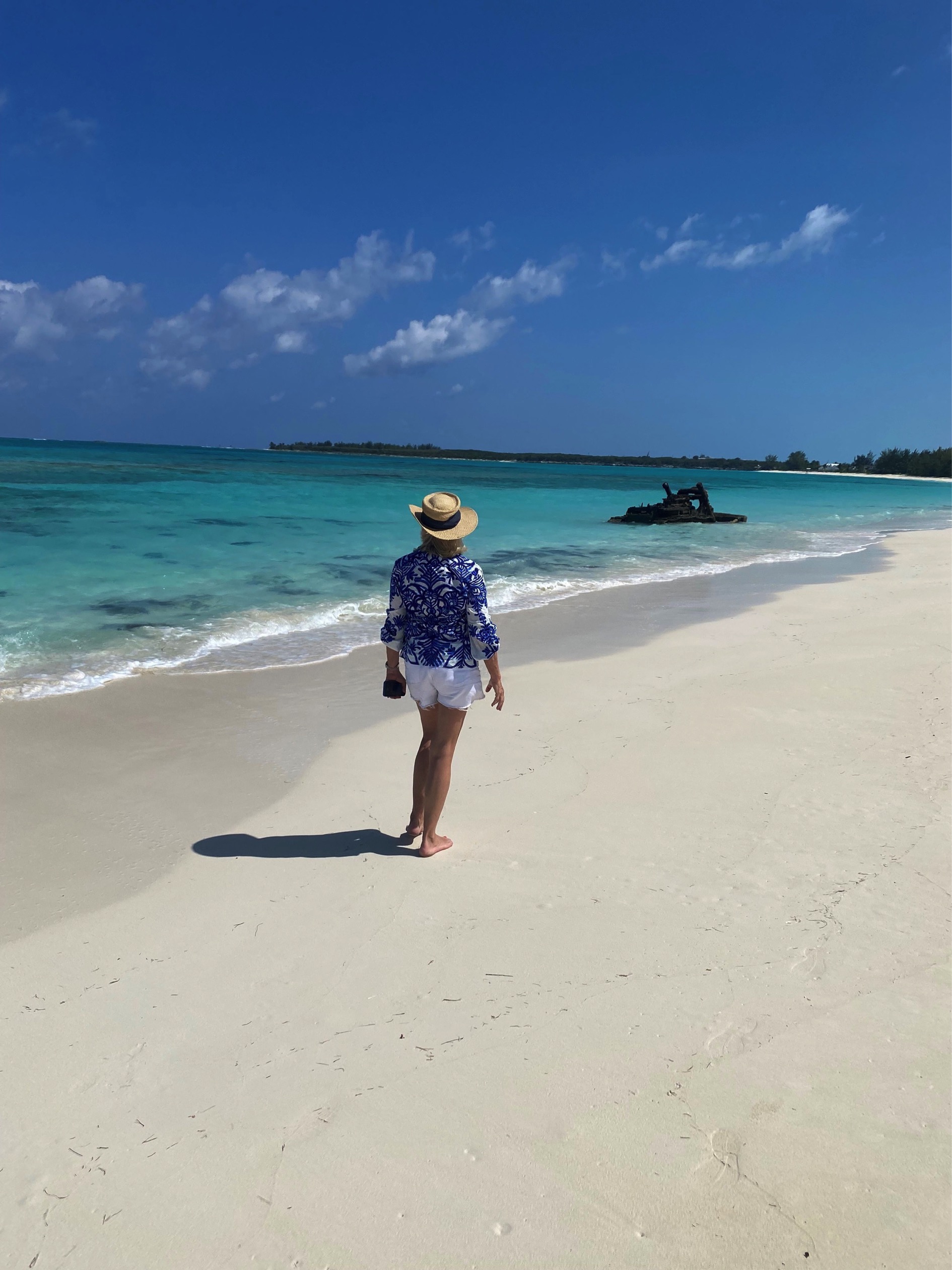 Guest walking on the white sand beach near a shipwreck Great Exuma Bahamas