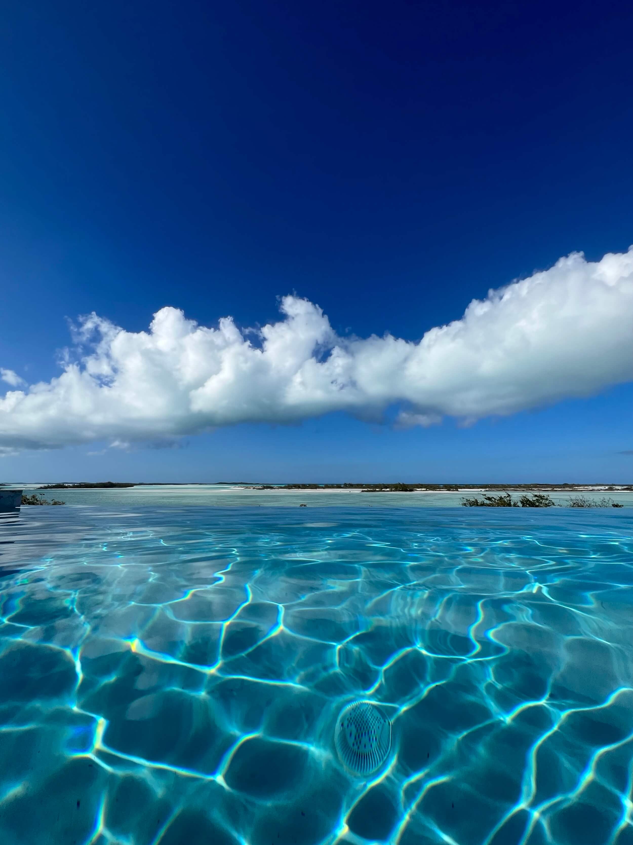 Infinity pool overlooking turquoise ocean and sandbar Great Exuma Bahamas